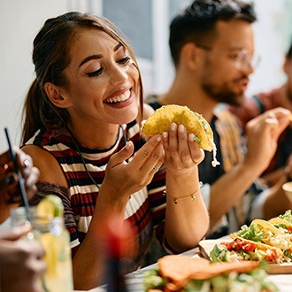 Woman smiling while eating lunch with friends at restaurant