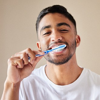 Man smiling while brushing his teeth