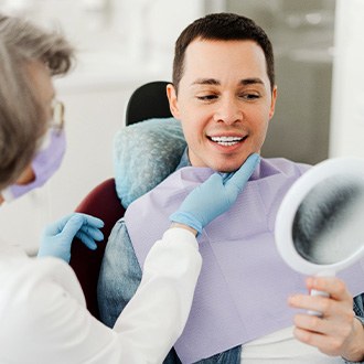 Man smiling at reflection in mirror with dentist