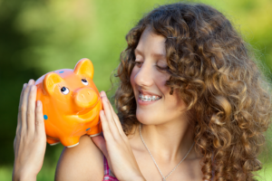 a girl with braces holding a piggy bank